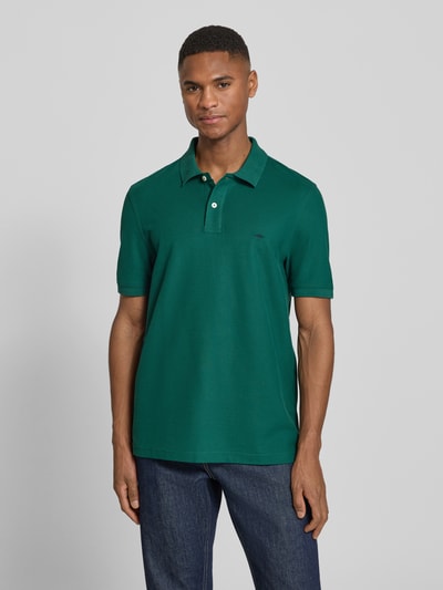 Männermodel trägt Regular Fit Poloshirt mit Logo-Stitching von Fynch-Hatton in Dunkelgrün, reine Baumwolle, Polokragen, Nahaufnahme Oberkörper.