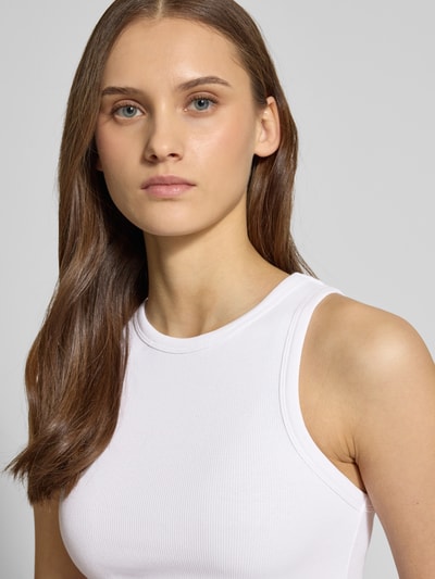 Modelka nosi Tanktop in Ripp-Optik von REVIEW w kolorze białym, bawełniano-elastanowy materiał, dopasowany krój, okrągły dekolt, zbliżenie na górną część ciała