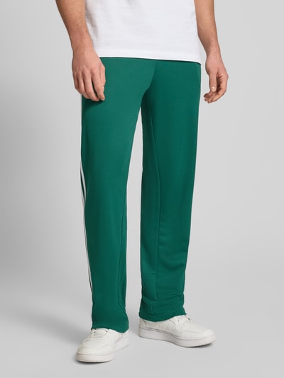 Mannenmodel draagt Sweatpants met elastische tailleband van adidas Originals, losvallende fit, label-stitching, steekzakken, binnenbeenlengte maat M 81 cm, volledige lichaamsvooraanzicht.