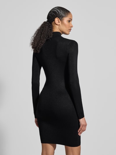 Frauenmodel trägt Slim Fit Kleid aus Viskose-Mix mit Ziersteinbesatz Modell 'Lucy' von Guess, Schwarz, semitransparent, Ganzkörperansicht Rückansicht. Damen Kleid, langärmelig, Stehkragen, Rückenlänge bei Größe S 93 cm, Brustweite 34 cm, Ärmellänge 63 cm.