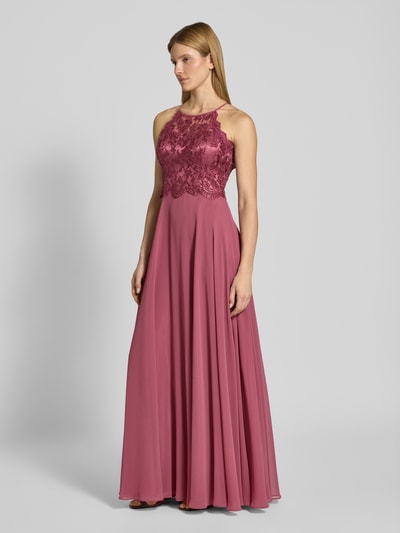 Modelka nosi 'Abendkleid mit Spitze und Cut Out' od V.M., różowy szyfon, koronka, długość maxi, A-linia, zamek, szerokość w rozmiarze 36: 35 cm; długość tyłu: 143 cm, widok całej sylwetki z przodu.