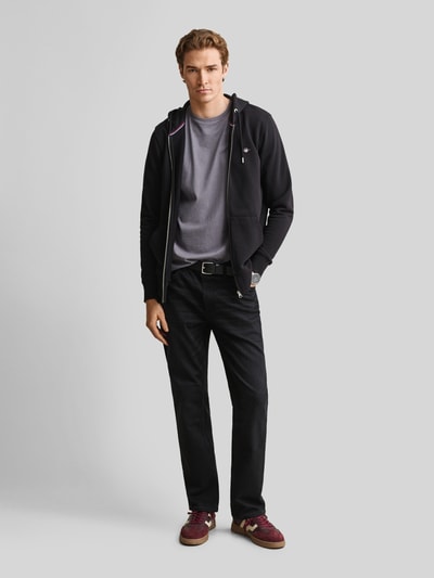 Männermodel trägt Regular Fit T-Shirt aus reiner Baumwolle von GANT in Grau, kombiniert mit dunkler Hose, Herren T-Shirt, Ganzkörperansicht von vorne.