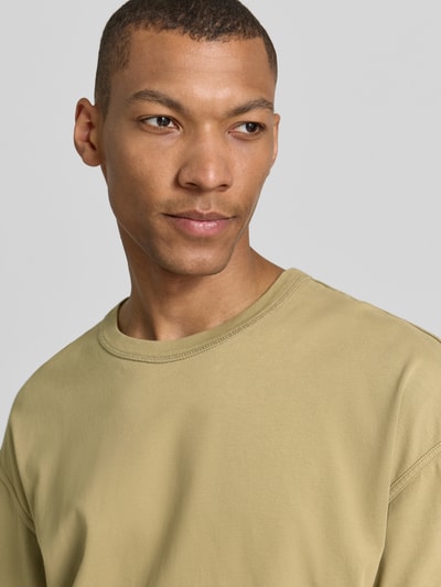 Männermodel trägt T-Shirt mit überschnittenen Schultern Modell 'FAZY' von American Vintage aus Reine Baumwolle in Beige, Nahaufnahme Oberkörper.