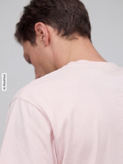 Männermodel trägt Regular Fit T-Shirt aus reiner Baumwolle von MCNEAL in zartem Rosa, weiche Textur, Nahaufnahme Rückansicht. Rückenlänge bei Größe M 66 cm, Rundhalsausschnitt, kurzärmeliges Design.