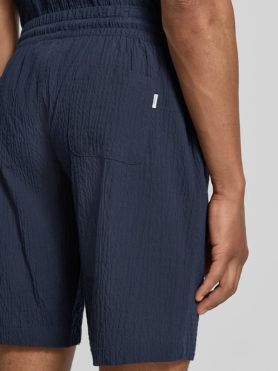 Männermodel trägt Shorts mit elastischem Bund und Strukturmuster von Lindbergh aus Baumwoll-Mix mit Stretch-Anteil, Detailaufnahme Rückansicht.