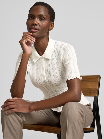 Frauenmodel trägt Slim Fit Poloshirt in Strick-Optik von Victoria Beckham aus Baumwoll-Mix, semitransparent und kurzärmelig, Nahaufnahme Oberkörper.