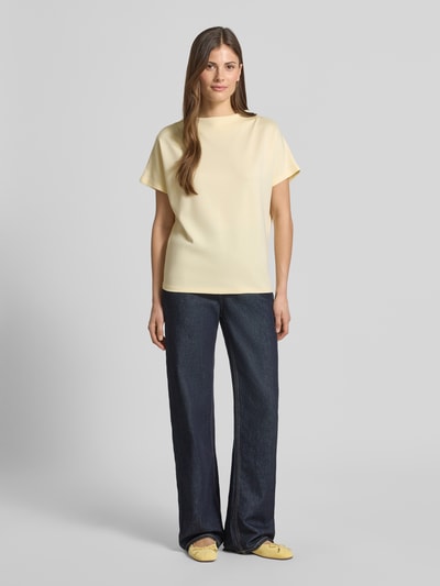 Vrouwenmodel draagt Regular Fit T-Shirt uit elastische viscosemix model 'Kiline' van Someday in lichtgeel met staande kraag, volledige lichaamsvooraanzicht. Ruglengte maat 36: 58 cm.