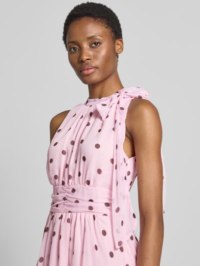 Frauenmodel trägt Abendkleid mit Rüschenbesatz Modell 'Marli' von Neo Noir, rosa mit braunen Punkten, Zierschleife, Nahaufnahme Oberkörper.