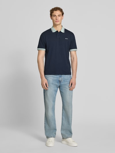 Männermodel trägt Regular Fit Poloshirt aus reiner Baumwolle Modell 'BLOCKS' von BOSS Orange, unifarben, Piqué, Ganzkörperansicht von vorne.