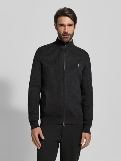 Męski model nosi Strickjacke mit Reißverschluss od Polo Ralph Lauren z bawełny, regular fit, czarny kolor, widok całej sylwetki z przodu.