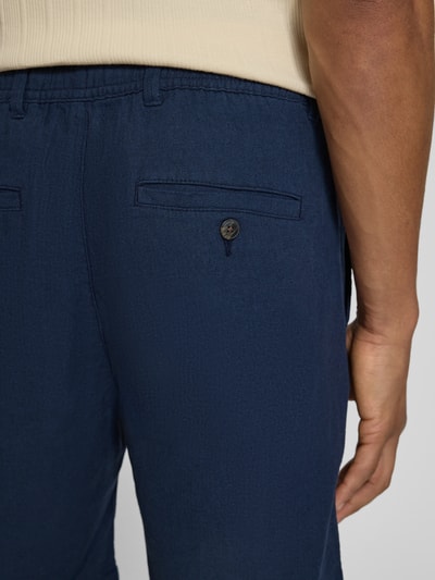 Männermodel trägt Regular Fit Chinoshorts aus Baumwoll-Leinen-Mix Modell 'BRODY' von SELECTED HOMME in Dunkelblau, Flammgarntextur, Detailaufnahme Rückenansicht.