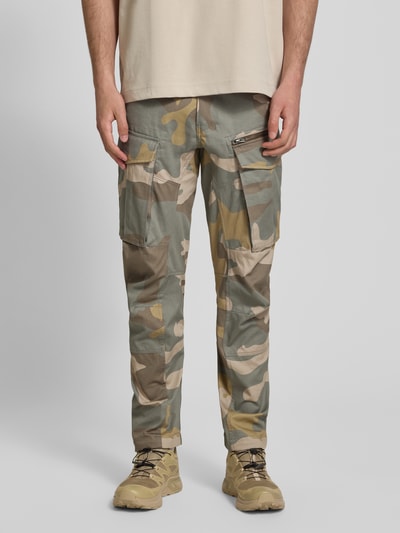 Männermodel trägt Tapered Cargohose aus reiner Baumwolle von g-star met all-over camouflagemotief, labelpatch, 5-pocketmodel, cargozakken, verstelbare pijpboord, knoop- en ritssluiting, riemlussen, low rise, versterkte knieën, materiaal puur katoen, ganzkörperansicht van voren.