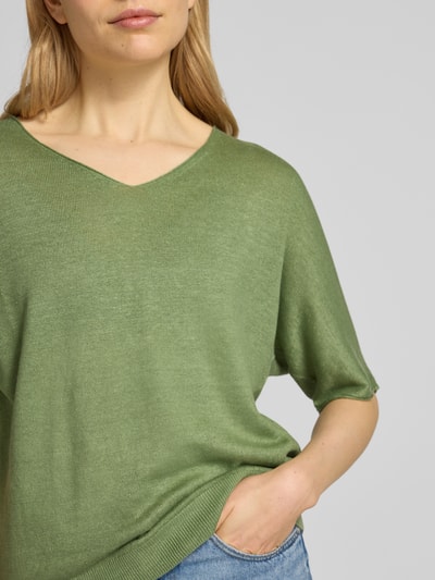 Frauenmodel trägt Relaxed Fit Strickshirt aus reinen Leinen in Strick-Optik von Luisa Cerano in Grün, V-Ausschnitt, Halbarm, elastischer Bund, Nahaufnahme Oberkörper. Rückenlänge 56 cm, Ärmellänge 28 cm, Größe 36.