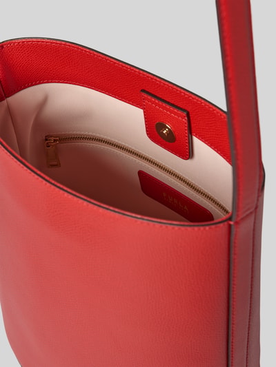 Produktfoto, czerwono-beżowa torebka typu bucket bag z aplikacją z logo, główna przegroda z zapięciem na magnes, przegródka zapinana na zamek błyskawiczny, regulowany pasek na ramię, model 'Roxie' od Furla, szerokość w rozmiarze 1: 24 cm, długość w rozmiarze 1: 26 cm, głębokość w rozmiarze 1: 17 cm, długość paska na ramię w rozmiarze 1: 67 cm