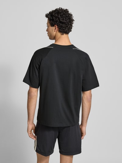 Männermodel trägt T-Shirt mit Label-Print von adidas Sportswear aus reiner Baumwolle in Schwarz, Regular-Fit, Rückansicht Ganzkörperansicht