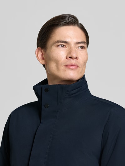 Männermodel trägt Parka mit Kapuze Modell 'HEKTOR' von Didriksons in Dunkelblau, glatte Textur, Nahaufnahme Oberkörper. Regular Fit, Stehkragen, verdeckter Reißverschluss, Ärmelriegel, Rückenlänge 99 cm, Schulterbreite 48 cm, Brustweite 50 cm, Ärmellänge 71 cm.