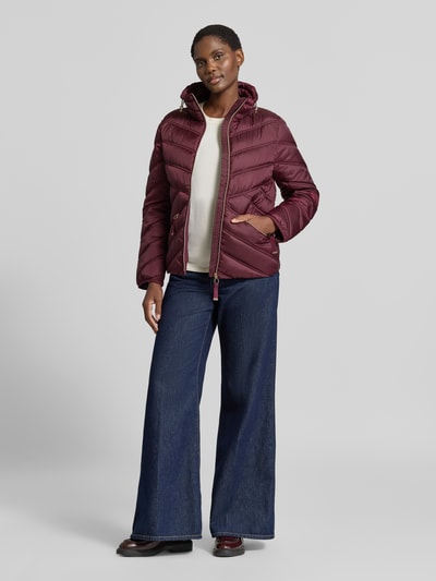 Vrouwenmodel draagt Steppjacke mit Stehkragen und Reißverschlusstaschen van Christian Berg Woman Selection in bordeaux, regular fit, ritssluiting, ritssluitzakken, lengte 61 cm, schouderbreedte 42 cm, borstwijdte 51 cm, mouwlengte 58 cm, volledige lichaamsweergave frontaal.