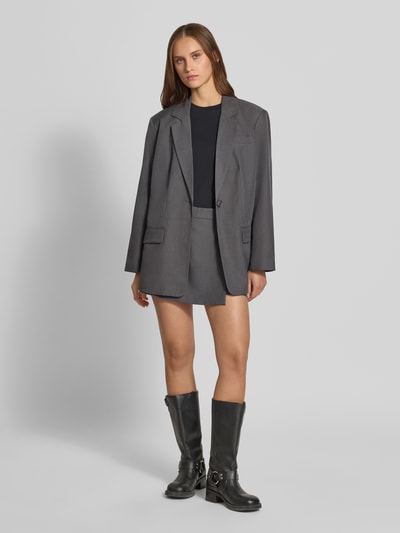Frauenmodel trägt Loose Fit Longblazer mit Reverskragen Modell 'LINDA' von ONLY in Grau, kombiniert mit schwarzem Shirt und Stiefeln, Ganzkörperansicht von vorne, Damen Longblazer von ONLY.