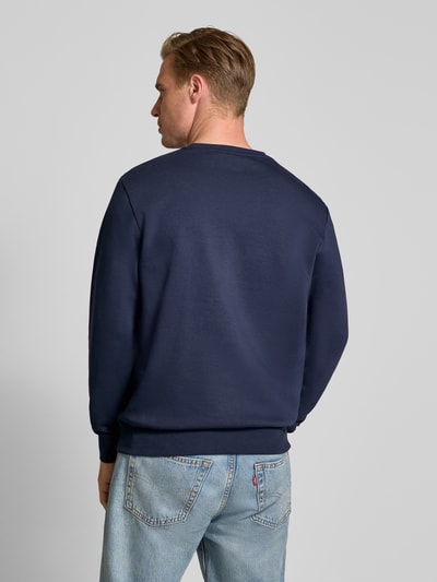 Männermodel trägt Relaxed Fit Sweatshirt aus Baumwoll-Mix von Tom Tailor in Dunkelblau, kombiniert mit Jeans, Ganzkörperansicht Rückansicht, Herren Sweatshirt von Tom Tailor.