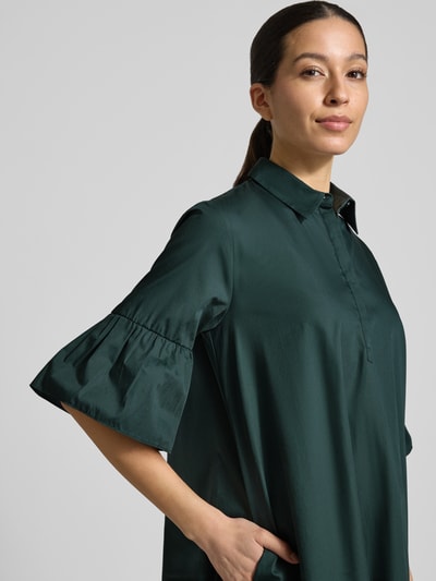 Frauenmodel trägt knielanges Hemdblusenkleid mit Kentkragen Modell 'EPOCHE' von EMME aus reiner Baumwolle, lockerer Schnitt, Volants, Nahaufnahme Oberkörper.