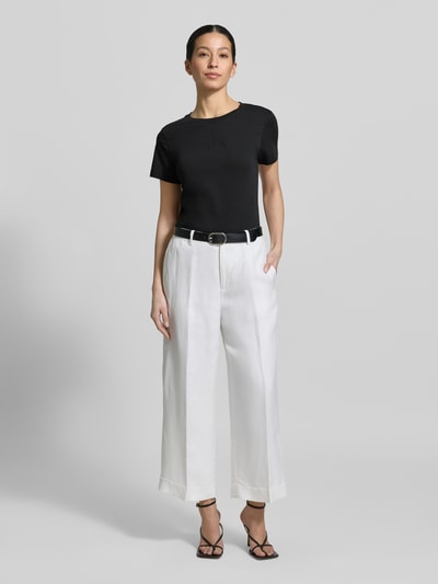 Vrouwenmodel draagt T-shirt met ronde hals en logo van Armani Exchange, puur katoen, regular fit, ruglengte maat S 62 cm. Ganzörperaanzicht van voren.