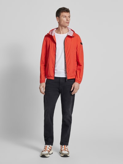 Mannenmodel draagt Peuterey Jacke mit Kapuze Modell 'NIGLE' in regular fit, rood, met capuchon, tweewegritssluiting, steekzakken, ganzkörperansicht van voren. Ruglengte maat M: 69 cm, schouderbreedte 47 cm, borstwijdte 56 cm, mouwlengte 68 cm.