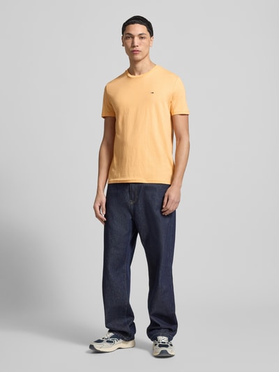 Mannenmodel draagt Slim Fit T-shirt uit katoenmix model 'JASPE HERITAGE' van Tommy Jeans, gemêleerde look, logostitching, korte mouw, materialenmix. Ganzkörperansicht van voren.