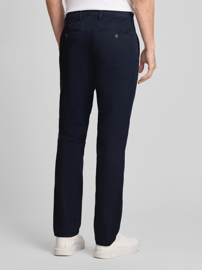 Männermodel trägt Slim Fit Chino mit Eingrifftaschen von GAP in Dunkelblau, Baumwoll-Elasthan-Mix, Ganzkörperansicht Rückansicht.