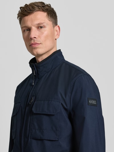 Männermodel trägt Jacke mit Stehkragen von NAUTGÅRD in Dunkelblau mit Reißverschluss, Brusttaschen, Regular Fit, Nahaufnahme Oberkörper. Rückenlänge bei Größe M: 73 cm, Schulterbreite: 45 cm, Brustweite: 49 cm, Ärmellänge: 67 cm.