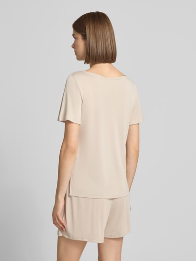 Kobiece modelka nosi damski t-shirt o kroju regular fit model 'PCANORA' od PIECES w jednolitym beżowym kolorze, widok całej sylwetki z tyłu.