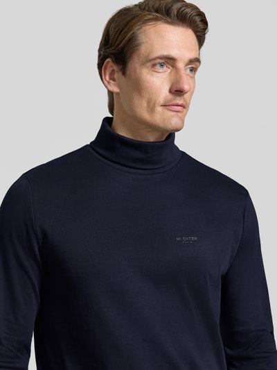 Männermodel trägt Longsleeve mit Rollkragen von HECHTER PARIS in dunklem Blau, reine Baumwolle, Label-Details, Nahaufnahme Oberkörper.