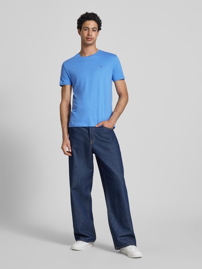 Męski model nosi Slim Fit T-Shirt Modell 'TJM XSLIM JASPE HTR TEE E' od Tommy Jeans, niebieski, jednolity, logo, krój slim fit, dekolt w serek, krótki rękaw, widok całej sylwetki z przodu