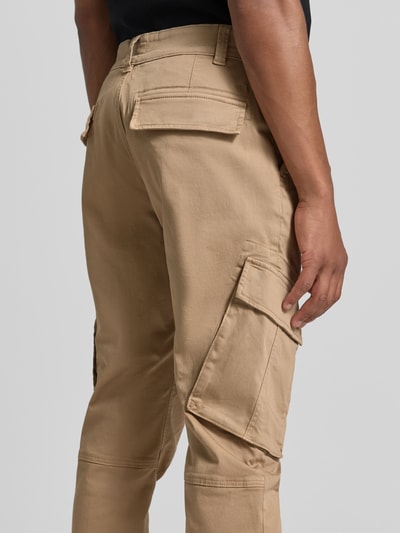 Männermodel trägt Straight Fit Cargohose aus Baumwoll-Mix von MCNEAL in Beige, mehrere Taschen, Struktur glatt, Ganzkörperansicht Rückansicht. Elastischer Material-Mix, Eingriff- und Gesäßtaschen, Knopf- und Reißverschluss, Bundweite 45 cm, Innenbeinlänge 80 cm.