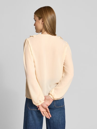 Frauenmodel trägt Bluse mit Rüschen und V-Ausschnitt von Marc Cain in zartem Beige, gerade Form, elastische Ärmelabschlüsse, Rückenansicht.