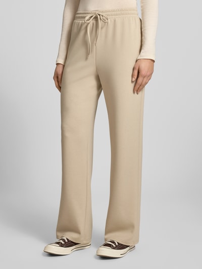 Frauenmodel trägt beige Regular Fit Sweatpants mit Viskose-Anteil Modell 'TALIA' von Pieces, unifarbene Sweat-Textur, Ganzkörperansicht von vorne.