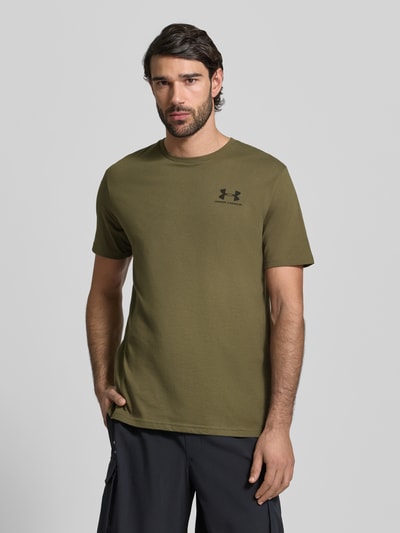 Męski model nosi Regular Fit T-Shirt mit Logo-Print Modell 'Left' von Under Armour z mieszanki bawełny, okrągły dekolt, kolor khaki, nadruk z logo, długość tyłu w rozmiarze M: 72 cm, Ganzkörperansicht von vorne.