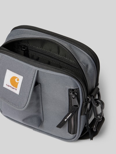 Produktfoto, Crossbody Bag mit Logo-Patch von Carhartt Work In Progress in Grau mit geteiltem Hauptfach, Reißverschluss und Logo-Patch, textile strukturierte Oberfläche, verstellbarer und abnehmbarer Schulterriemen, Größe 17x18x6 cm, Länge Schulterriemen 80 cm.
