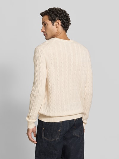 Männermodel trägt Slim Fit Strickpullover aus reinem Kaschmir mit Zopfmuster von Christian Berg Men, cremefarben, Rückansicht Ganzkörperansicht.