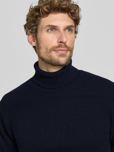 Männermodel trägt Slim Fit Rollkragenpullover aus Woll-Mix Modell 'Karl' von Casual Friday in Dunkelblau, gerippte Abschlüsse, Nahaufnahme Oberkörper.
