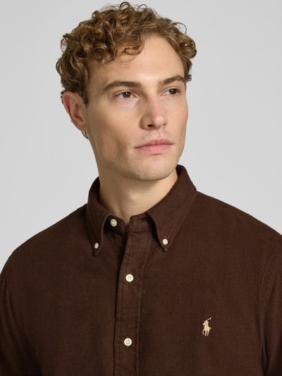 Männermodel trägt Custom Fit Freizeithemd aus reiner Baumwolle von Polo Ralph Lauren in Dunkelbraun mit Knopfleiste, Nahaufnahme Oberkörper.