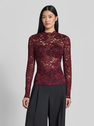 Frauenmodel trägt Slim Fit Longsleeve aus floraler Spitze Modell 'Lacey' von YAS in Dunkelrot, semitransparent, Ganzkörperansicht von vorne.