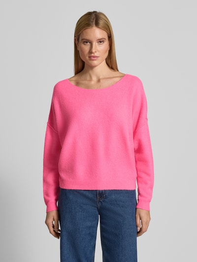 Modelka nosi różowy Oversized Strickpullover mit U-Boot-Ausschnitt Modell 'DAMSVILLE' von American Vintage, mieszanka materiałów z domieszką wełny, krój oversize, ściągacze, długość tyłu 48 cm, długość rękawa 44 cm, widok całej sylwetki z przodu.