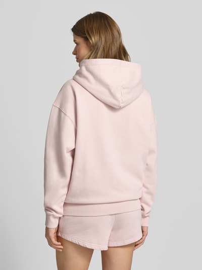 Frauenmodel trägt Oversized Sweatjacke mit Label-Stitching Modell 'CLARITA' von Pegador aus Baumwoll-Mix in zartem Rosaton, Ganzkörperansicht Rückansicht.