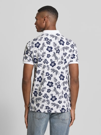 Męski model nosi Slim Fit Poloshirt aus reiner Baumwolle od Polo Ralph Lauren, efekt: wzór na całej powierzchni, kołnierzyk polo, detal z logo, dekolt w serek, krótki rękaw, prążkowane wykończenia, wykończenie z rozcięciami po bokach, asymetryczny dół, wykończenie: pika, skład: czysta bawełna, widok całej sylwetki z tyłu.