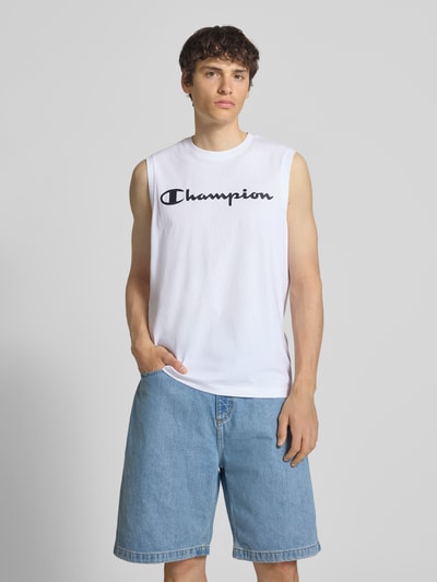 Männermodel trägt Top mit Logo und Rundhalsausschnitt von CHAMPION, weiß, Baumwoll-Mix, Regular-Fit, Rückenlänge 69 cm, Ganzkörperansicht von vorne.