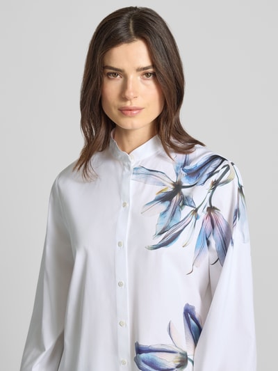 Frauenmodel trägt Bluse mit Mao-Kragen und Knopfleiste von Marc Cain aus reiner Baumwolle, weiße Basis, florale Prints, Nahaufnahme Oberkörper.