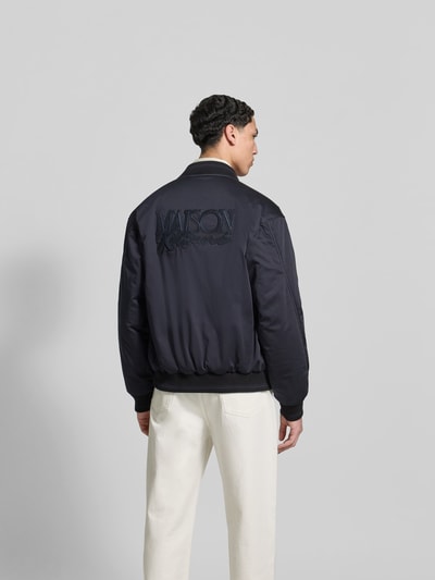 Männermodel trägt Blouson mit Stehkragen von MAISON KITSUNÉ in Dunkelblau, lockere Passform, elastische Abschlüsse, Ganzkörperansicht Rückansicht