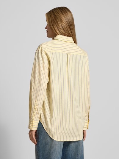 Frauenmodel trägt Relaxed Fit Bluse mit Brusttasche von Gant aus reiner Baumwolle in Gelb mit blauen Streifen, Hemdblusenkragen, Knopfleiste, Rückenlänge 73 cm bei Größe 36, Ärmellänge 57 cm, Ganzkörperansicht Rückansicht.