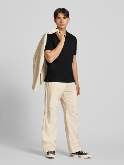 Männermodel trägt Regular Fit Poloshirt mit Strukturmuster Modell 'AUSTIN' von Jack & Jones, Baumwoll-Mix, schwarze Farbe, Ganzkörperansicht von vorne.
