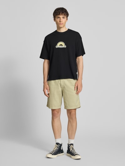 Männermodel trägt T-Shirt mit Label-Print und Rundhalsausschnitt von Jack & Jones in Schwarz, Regular Fit, reine Baumwolle, Ganzkörperansicht von vorne.